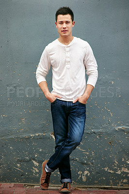 Buy stock photo Portrait of a handsome young man standing with his hands in his pockets against a grey wall