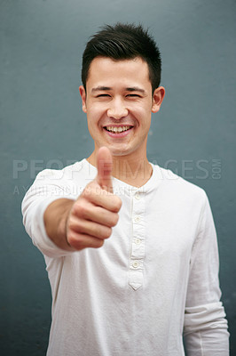 Buy stock photo Studio portrait of a handsome young man showing thumbs up against a grey background