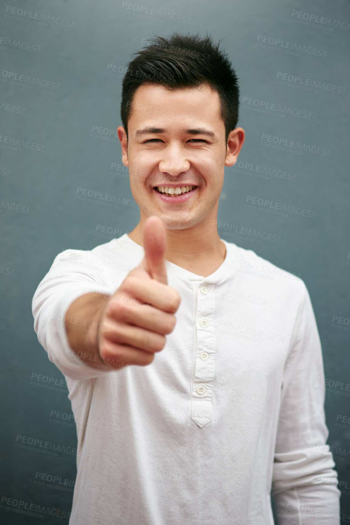 Buy stock photo Studio portrait of a handsome young man showing thumbs up against a grey background