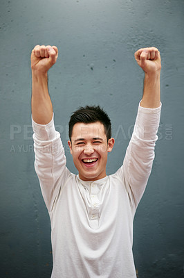 Buy stock photo Studio portrait of a handsome young man with his arms raised against a grey background