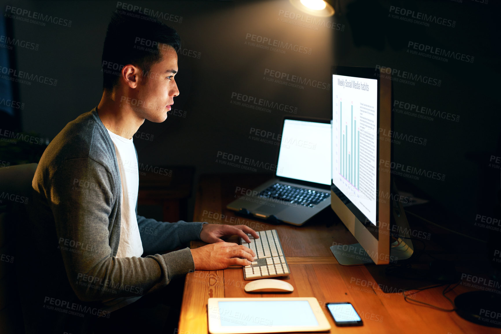 Buy stock photo Shot of a handsome young male programmer working late in his office