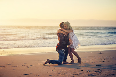 Buy stock photo Shot of a young man proposing to his girlfriend on the beach