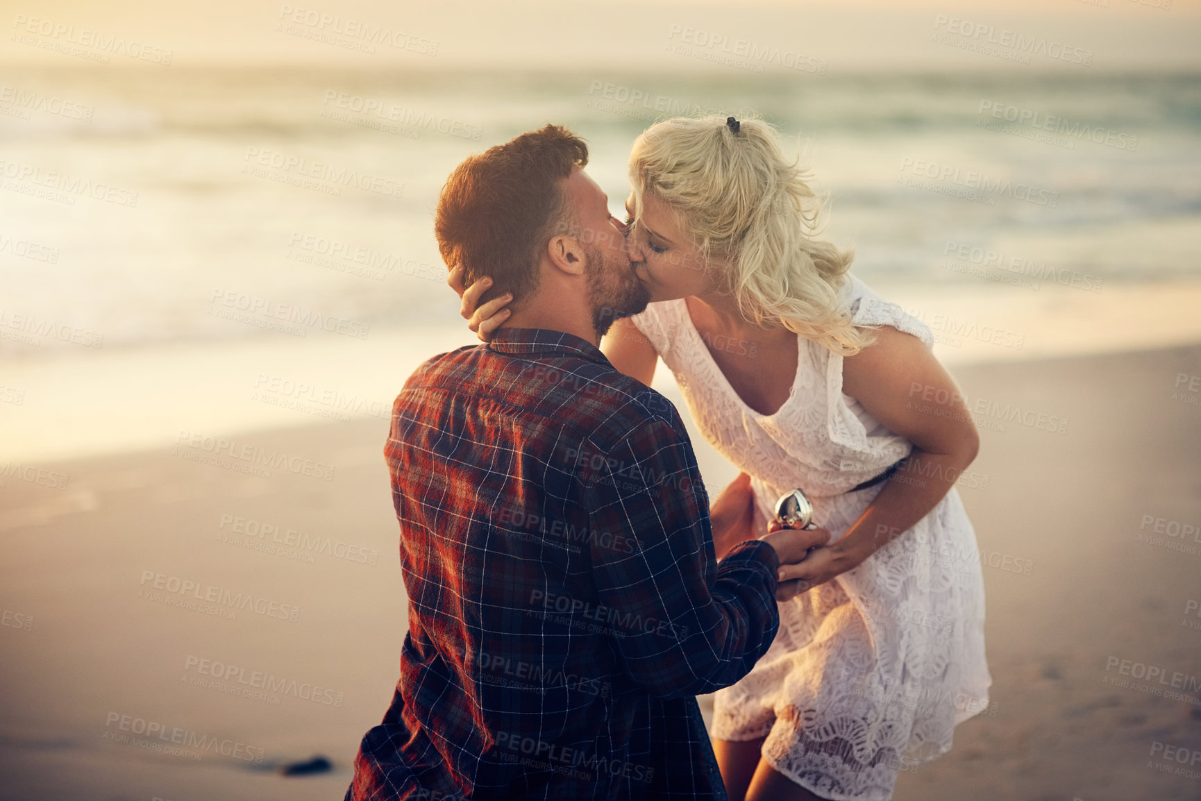 Buy stock photo Shot of a young man proposing to his girlfriend on the beach