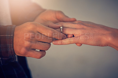 Buy stock photo Cropped shot of a young man putting an engagement ring on his girlfriend's finger