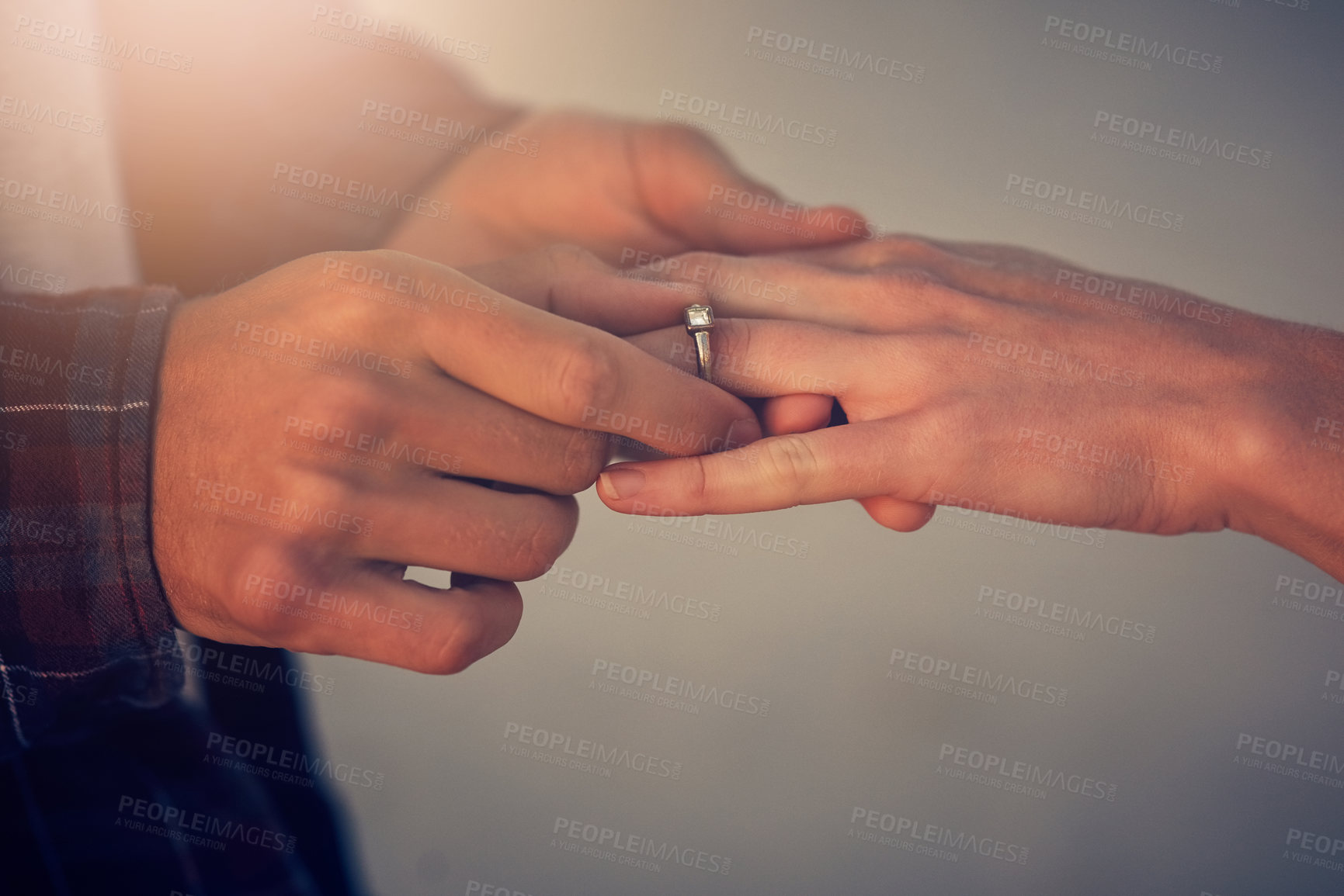 Buy stock photo Cropped shot of a young man putting an engagement ring on his girlfriend's finger