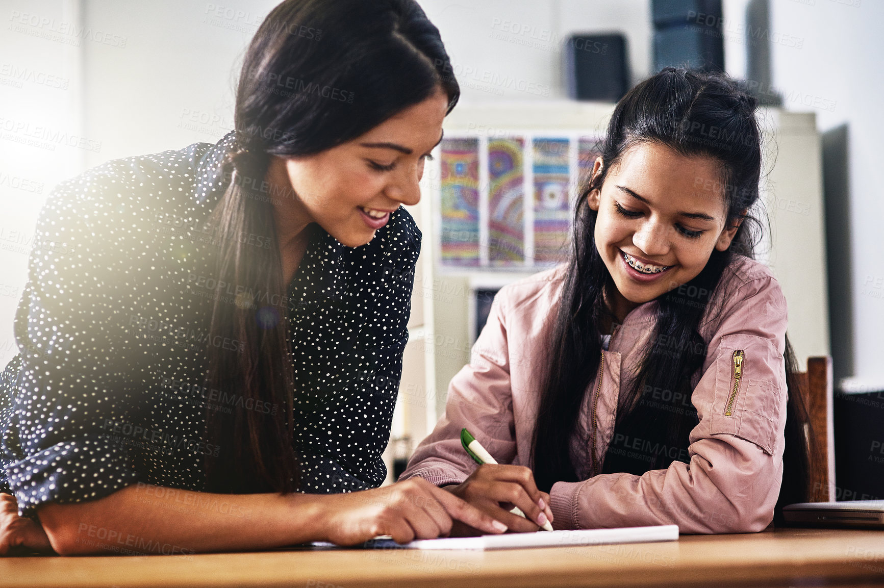 Buy stock photo Cropped shot of a young teacher helping a female student in her classroom