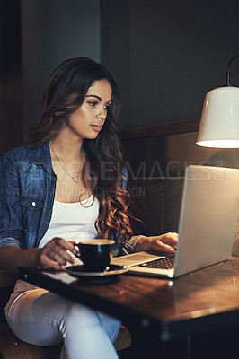 Buy stock photo Shot of a relaxed young woman using her laptop in a coffee shop