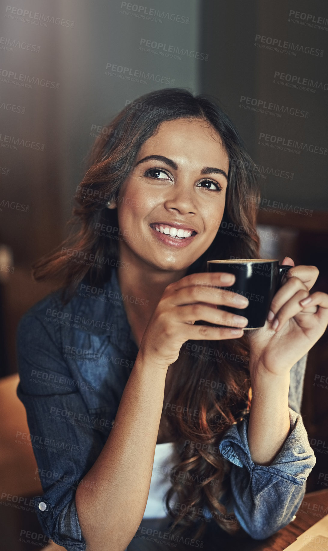 Buy stock photo Shot of a relaxed young woman enjoying a cup of coffee in a coffee shop