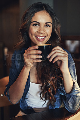 Buy stock photo Portrait of a relaxed young woman enjoying a cup of coffee in a coffee shop