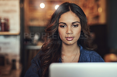 Buy stock photo Shot of a relaxed young woman using her laptop in a coffee shop