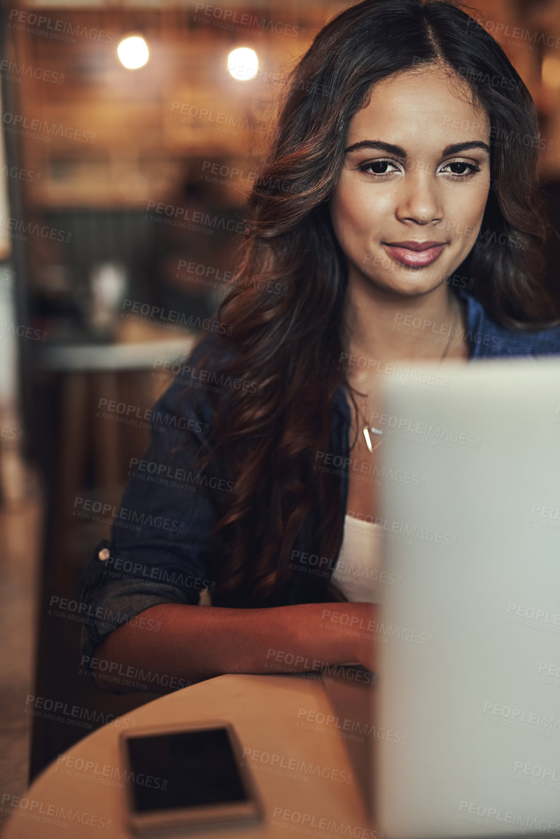 Buy stock photo Shot of a relaxed young woman using her laptop in a coffee shop