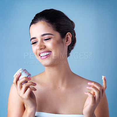 Buy stock photo Woman, smile and skincare product or moisturizing dermatology in studio, blue background or treatment. Female person, container and face lotion or sunscreen protection for health, self care or facial