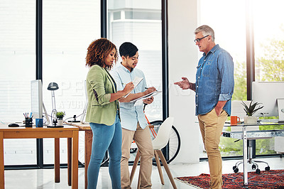 Buy stock photo Shot of a creative entrepreneur offering advice to two new colleagues in the office