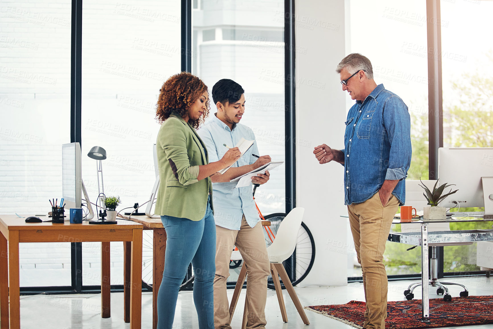 Buy stock photo Shot of a creative entrepreneur offering advice to two new colleagues in the office