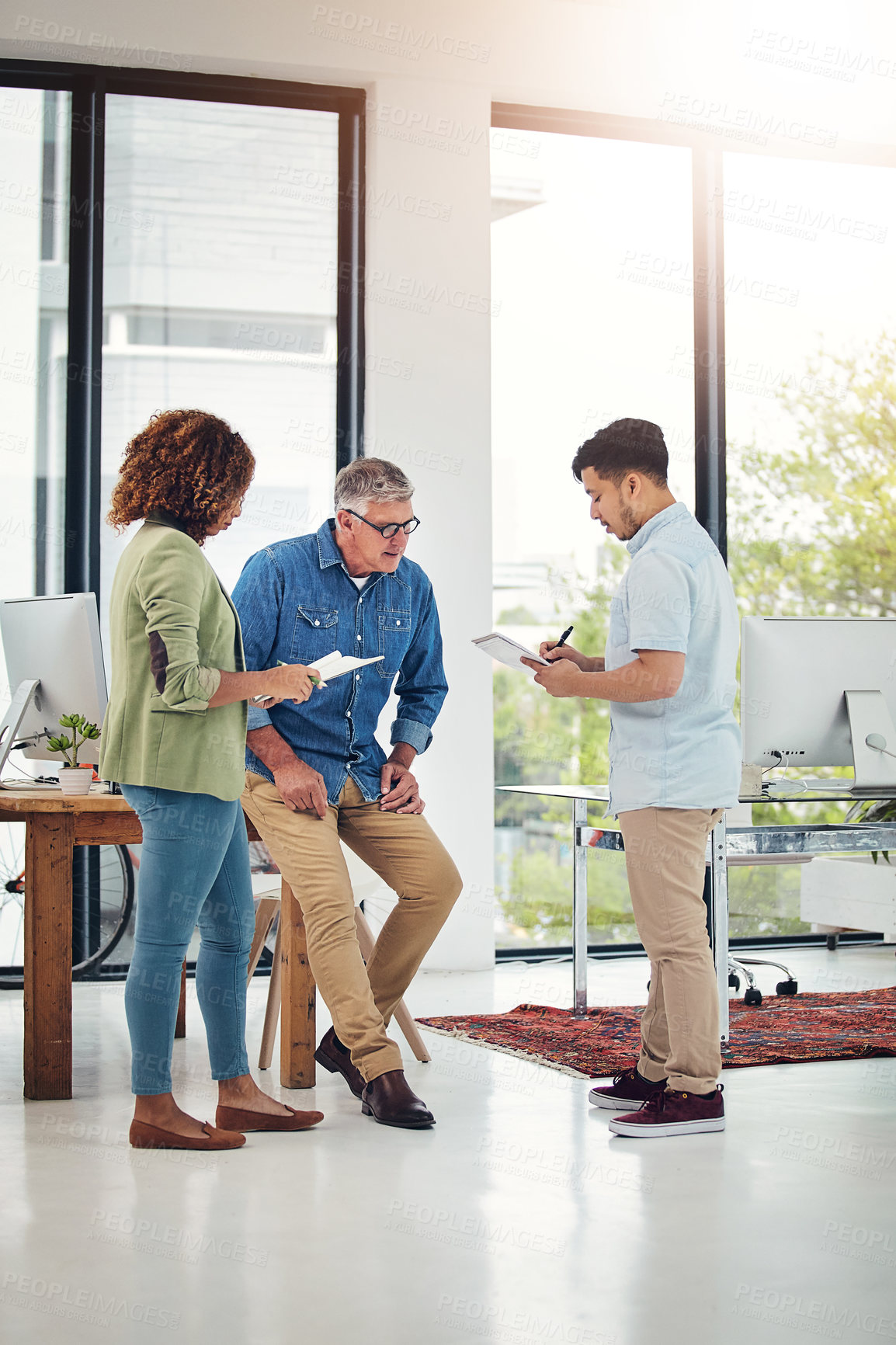 Buy stock photo Shot of a creative entrepreneur offering advice to two new colleagues in the office