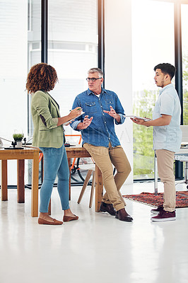Buy stock photo Shot of a creative entrepreneur offering advice to two new colleagues in the office