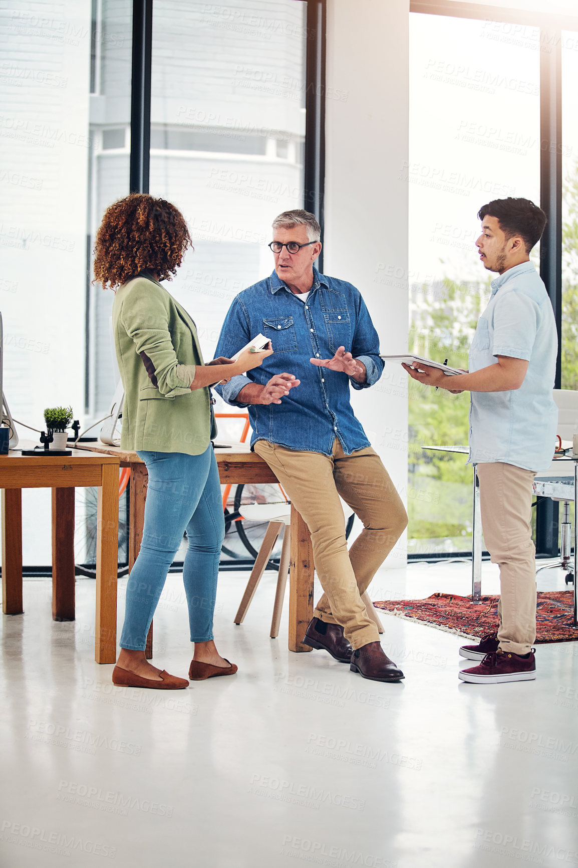 Buy stock photo Shot of a creative entrepreneur offering advice to two new colleagues in the office