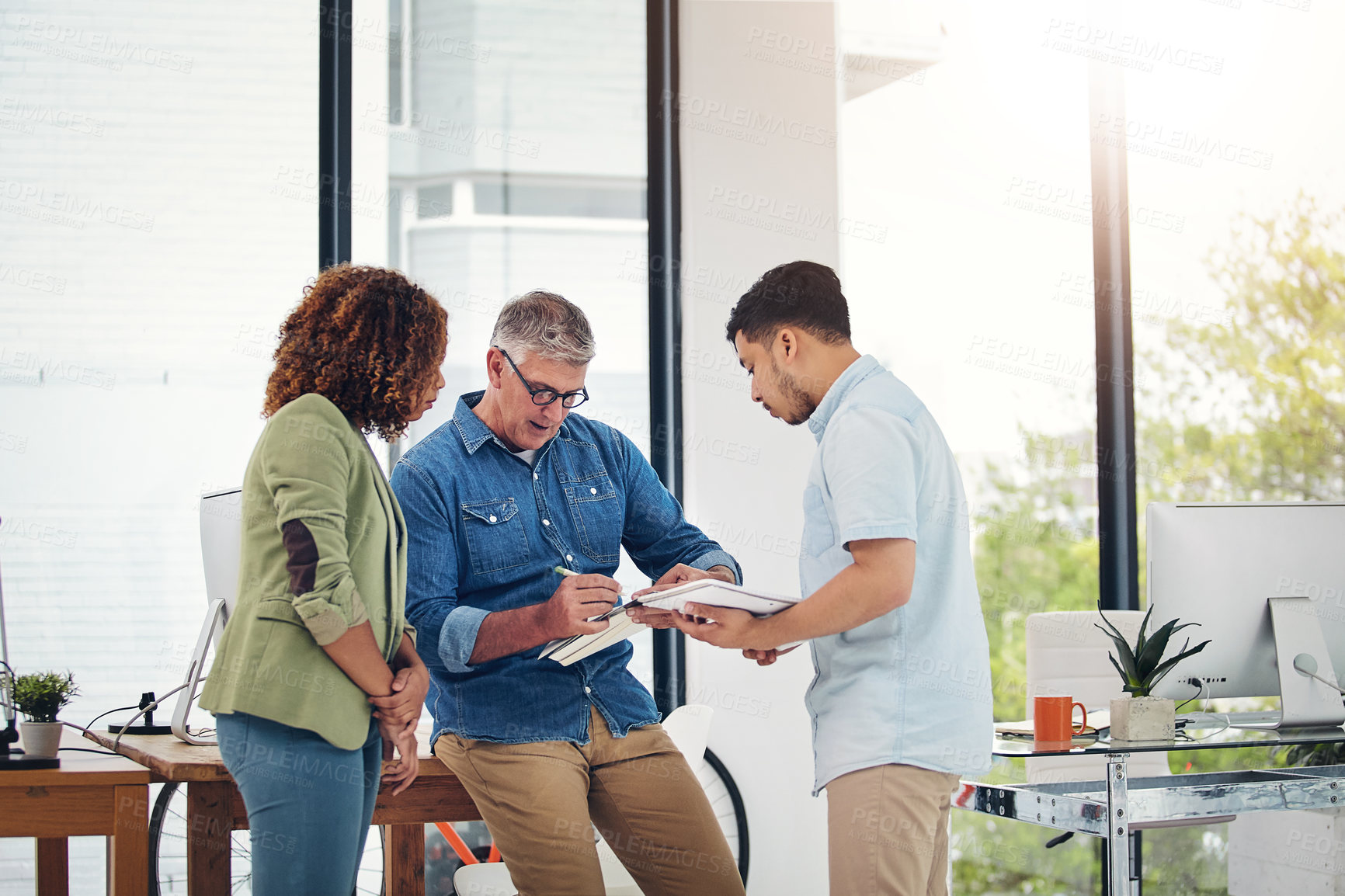 Buy stock photo Shot of a creative entrepreneur offering advice to two new colleagues in the office