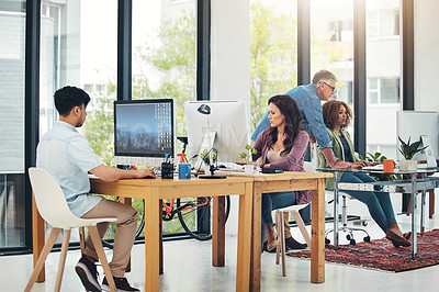 Buy stock photo Shot of group of creative colleagues working on a project together in their office