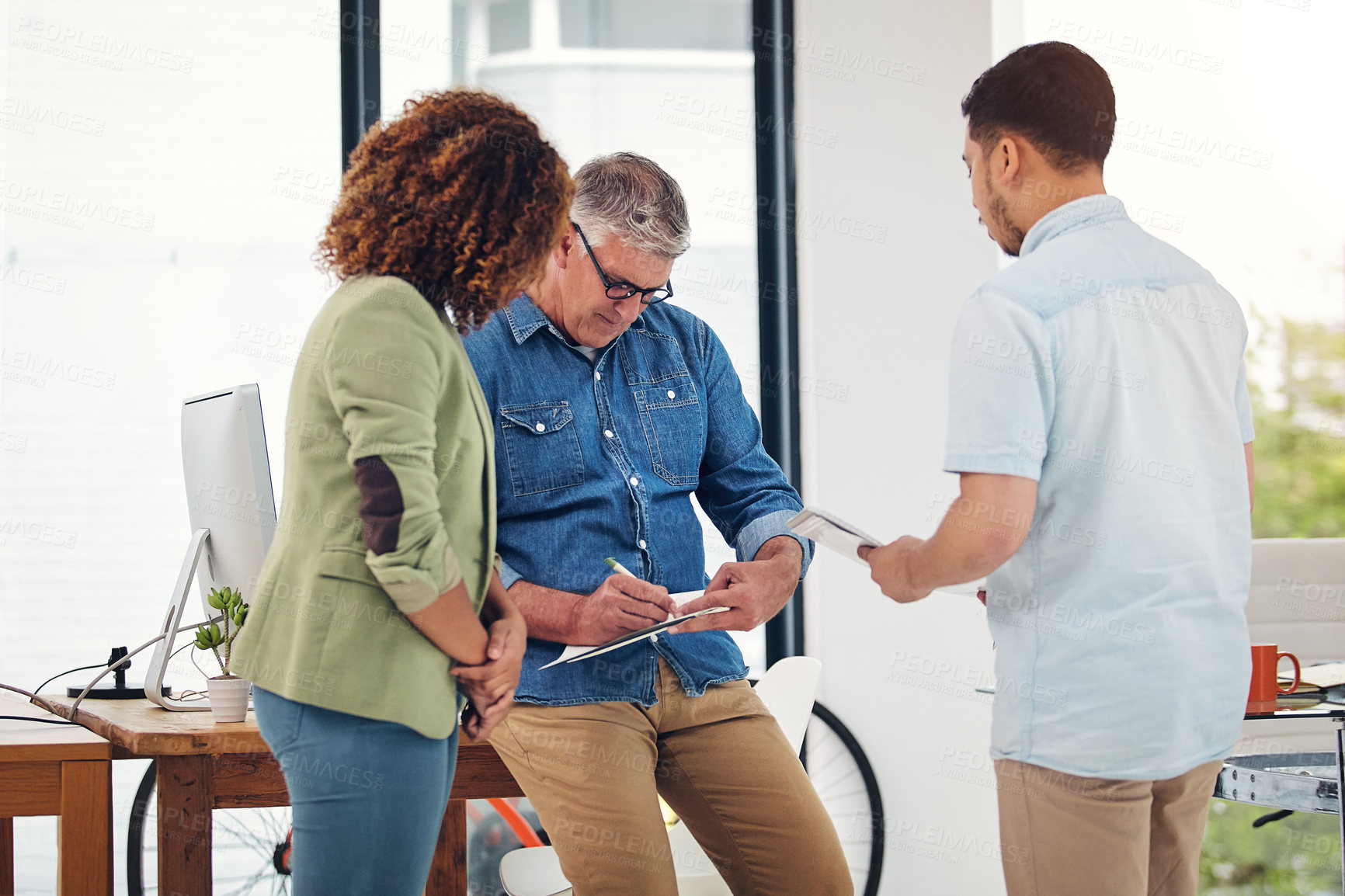 Buy stock photo Shot of a creative entrepreneur offering advice to two new colleagues in the office