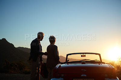 Buy stock photo Shot of an affectionate senior couple enjoying the sunset during a roadtrip