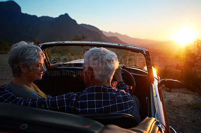 Buy stock photo Shot of an affectionate senior couple enjoying the sunset during a roadtrip