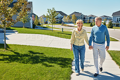 Buy stock photo Shot of a happy senior couple waking around their neighborhood together