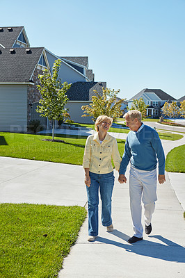 Buy stock photo Shot of a happy senior couple waking around their neighborhood together