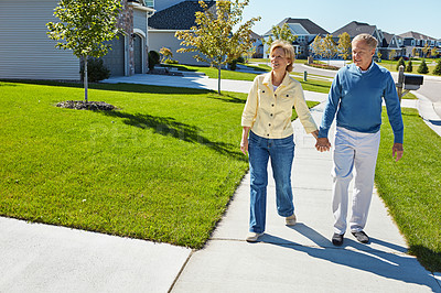 Buy stock photo Shot of a happy senior couple waking around their neighborhood together