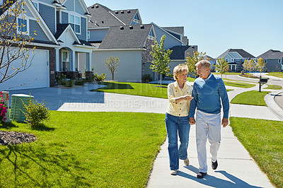 Buy stock photo Shot of a happy senior couple waking around their neighborhood together