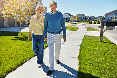 Buy stock photo Shot of a happy senior couple waking around their neighborhood together