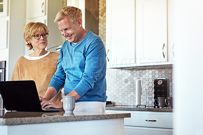 Buy stock photo Cropped shot of a mature couple using their laptop in the kitchen