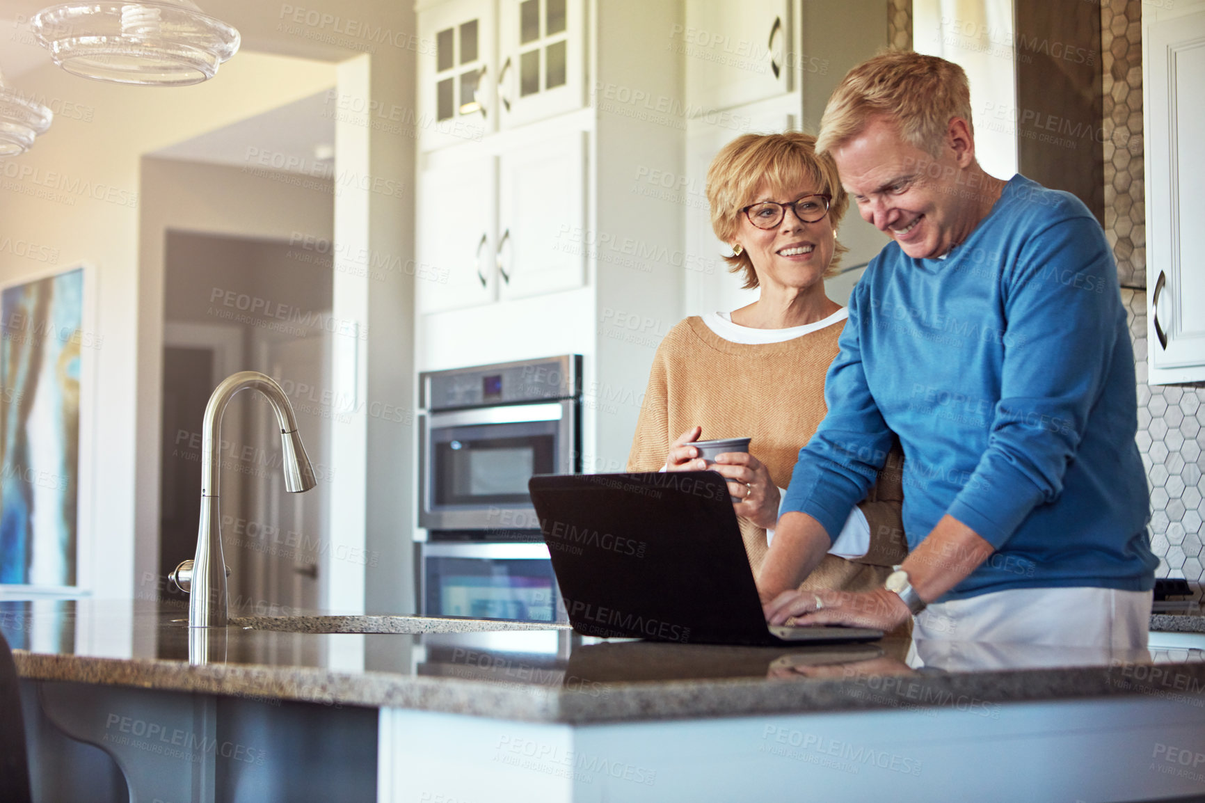 Buy stock photo Cropped shot of a mature couple using their laptop in the kitchen