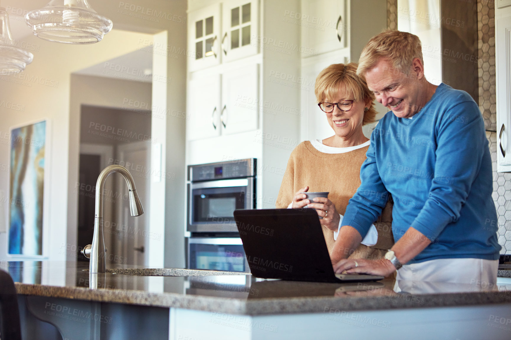 Buy stock photo Cropped shot of a mature couple using their laptop in the kitchen