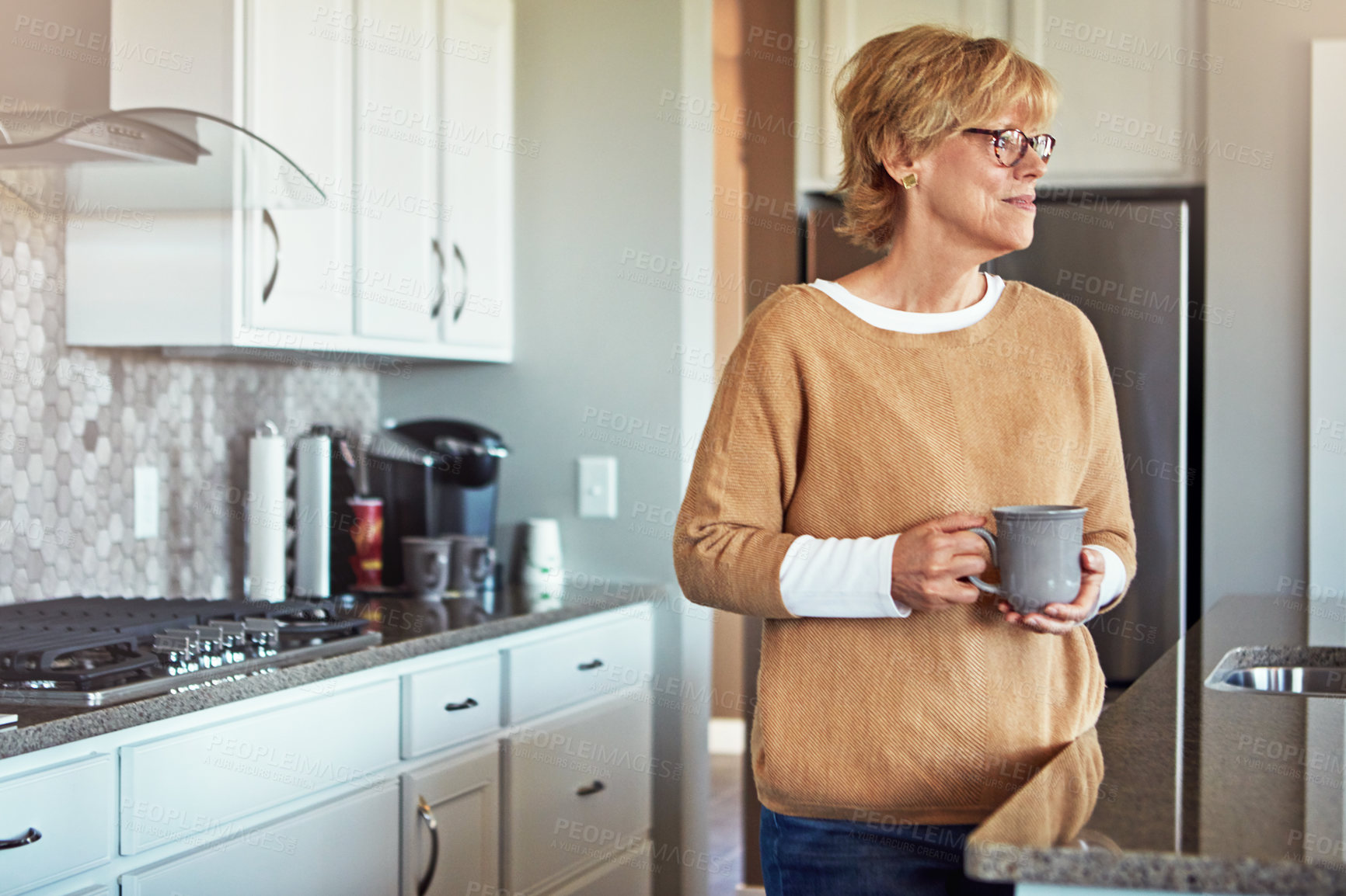 Buy stock photo Cropped shot of a mature woman drinking coffee in her kitchen