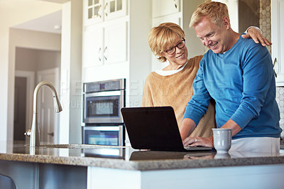 Buy stock photo Cropped shot of a mature couple using their laptop in the kitchen