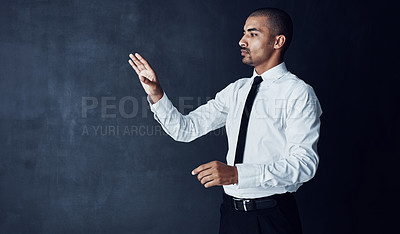 Buy stock photo Studio shot of a young businessman connecting to a user interface against a dark background