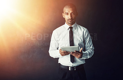 Buy stock photo Studio portrait of a young businessman using a digital tablet against a dark background