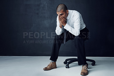 Buy stock photo Studio shot of a young businessman looking worried against a dark background