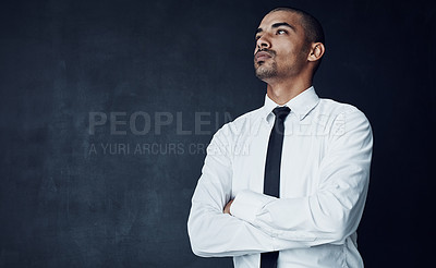Buy stock photo Studio shot of a young businessman looking thoughtful against a dark background