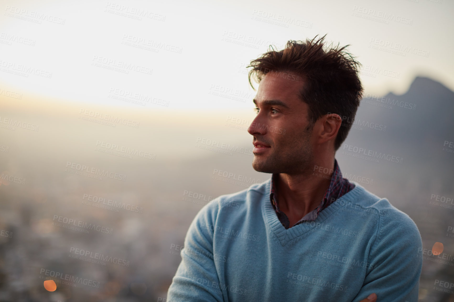 Buy stock photo Shot of a happy young man posing in front of a city view