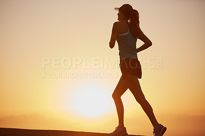 Buy stock photo Shot of a silhouetted young woman out for a run at sunrise