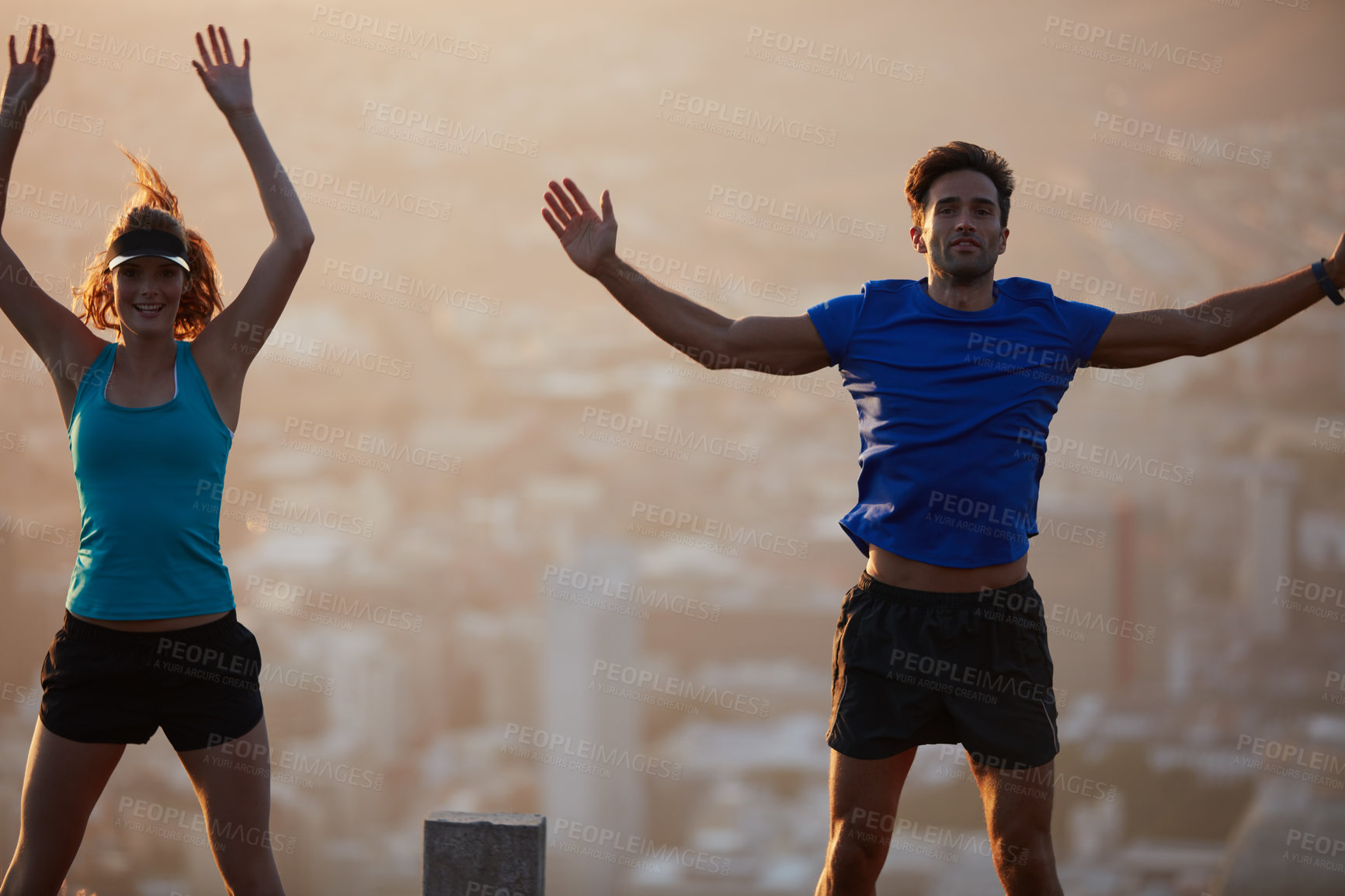 Buy stock photo Shot of an athletic young couple exercising above the city in the morning