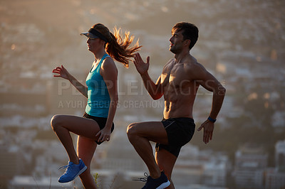 Buy stock photo Shot of an athletic young couple exercising above the city in the morning