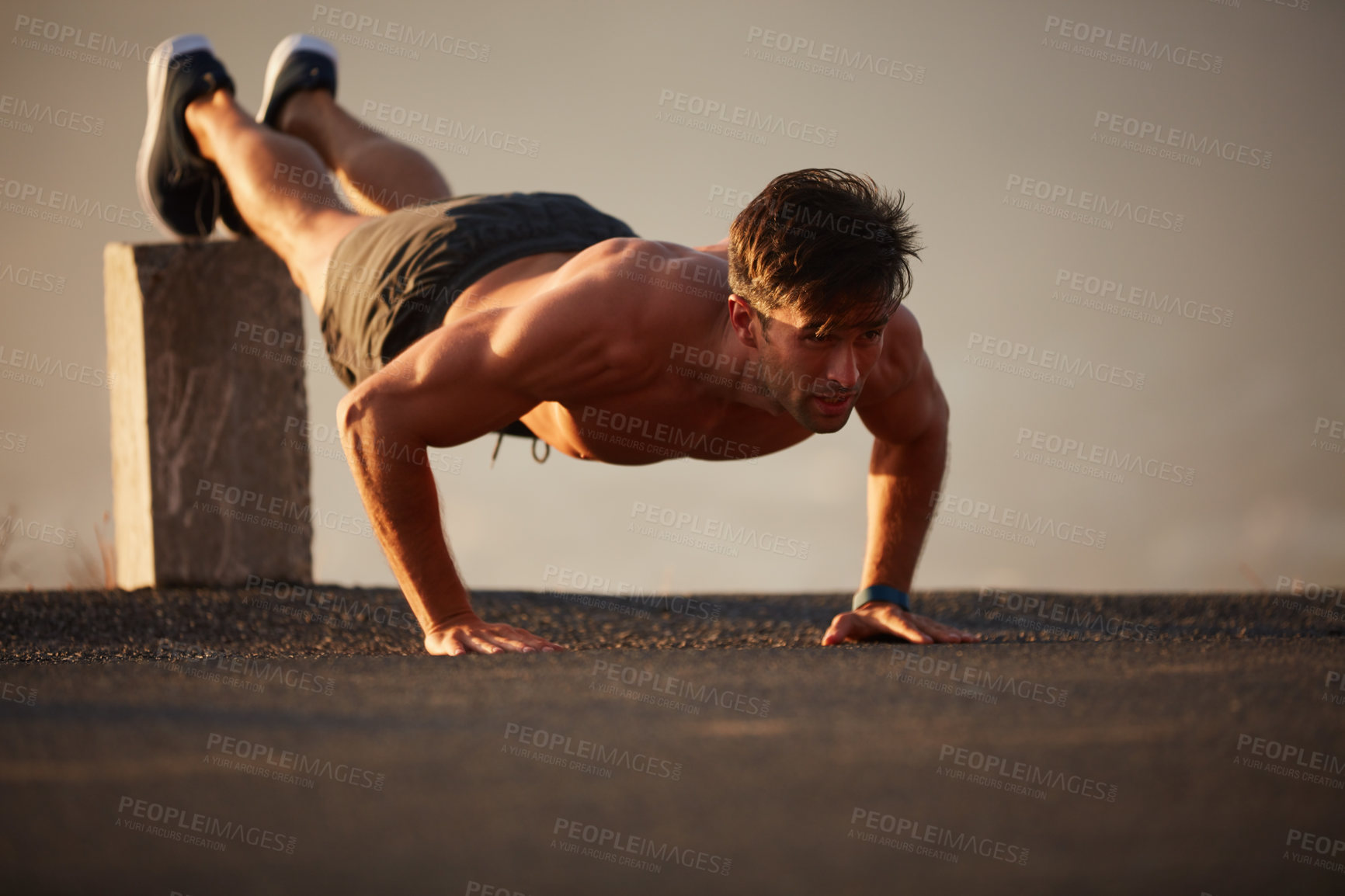 Buy stock photo Shot of a handsome shirtless man working out outside