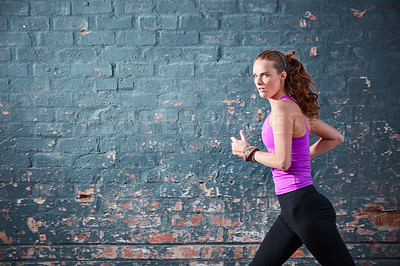 Buy stock photo Shot of a focussed young woman working out next to a brick wall outside