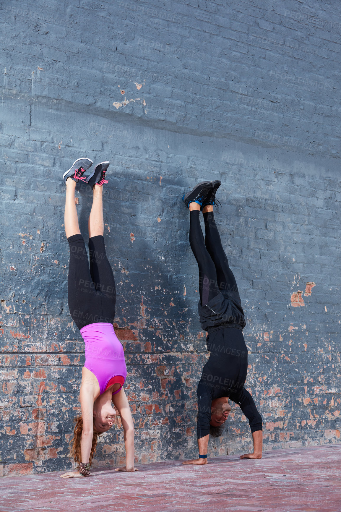 Buy stock photo Shot of two happy training partners working out next to a brick wall outside