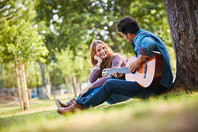 Buy stock photo Shot of a happy young couple enjoying a romantic day at the park