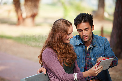 Buy stock photo Shot of a young couple using a tablet at the park