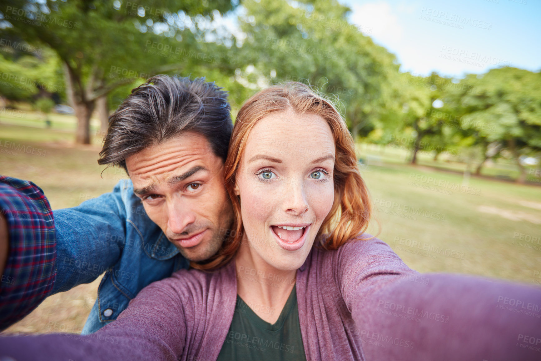 Buy stock photo Portrait of a young couple taking a selfie while out at the park